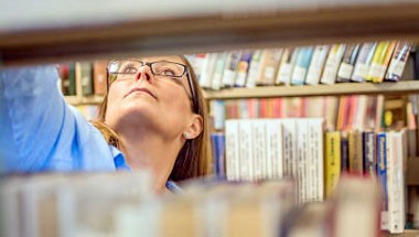 Trabajadora reubicando libros en los estantes