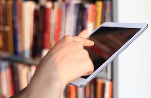 Person mit Tablet in einer Bibliothek