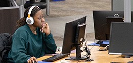 photo: student with headphones working at a library computer